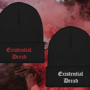 May include: Two black knit beanies with the phrase "Existential Dread" embroidered in red and white on the front.