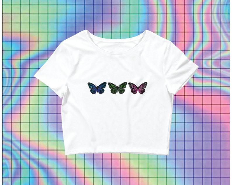May include: White cropped t-shirt with three colorful butterfly designs. The butterflies are blue, green, and pink with black outlines.