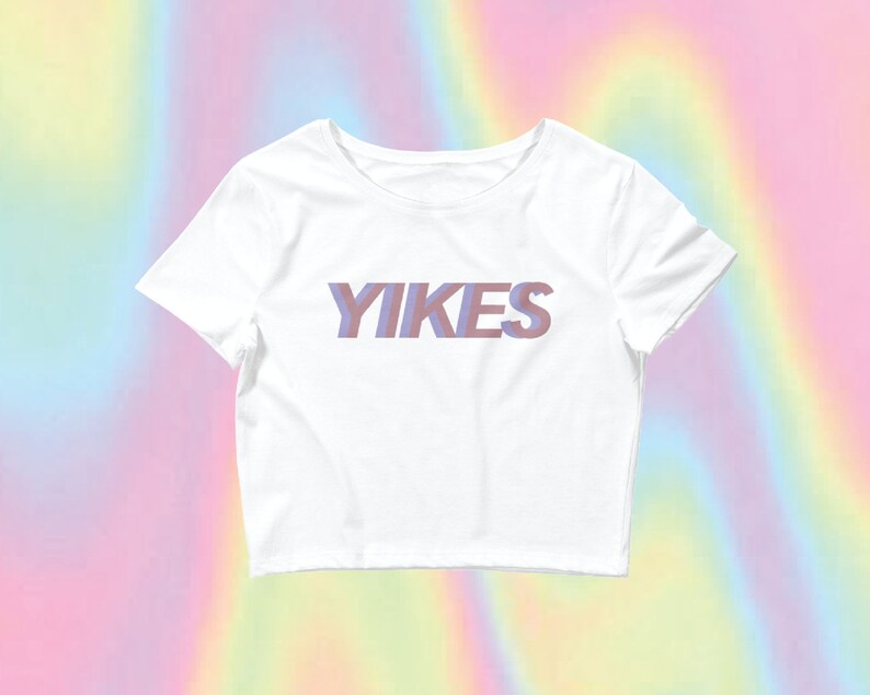 May include: White cropped t-shirt with the word "YIKES" printed in a purple and pink gradient.