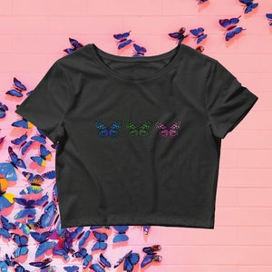 May include: A black cropped t-shirt with three colorful butterfly designs on the front. The butterflies are green, blue, and pink.