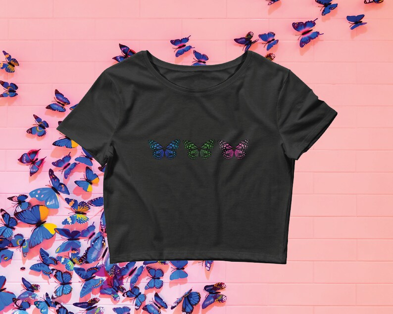 May include: A black cropped t-shirt with three colorful butterfly designs on the front. The butterflies are green, blue, and pink.