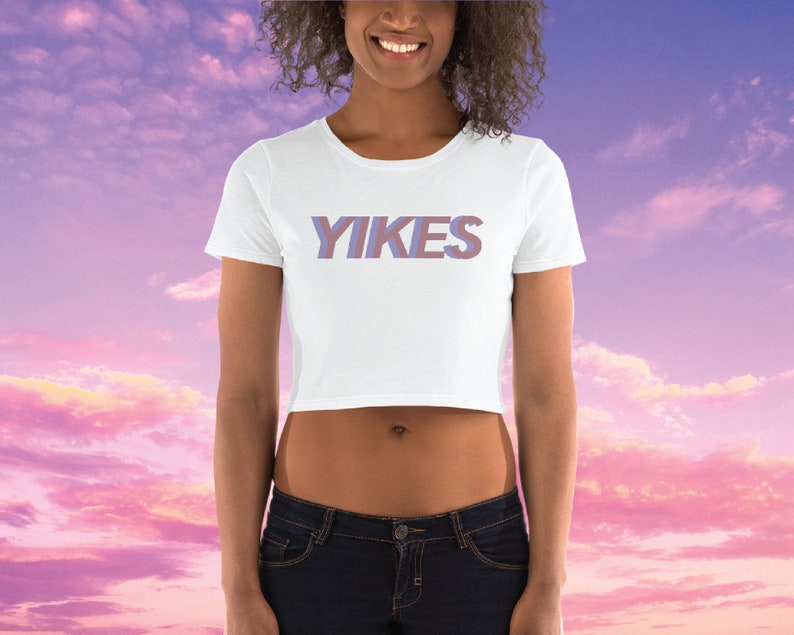 May include: White cropped t-shirt with the word "YIKES" printed in a purple and pink gradient.
