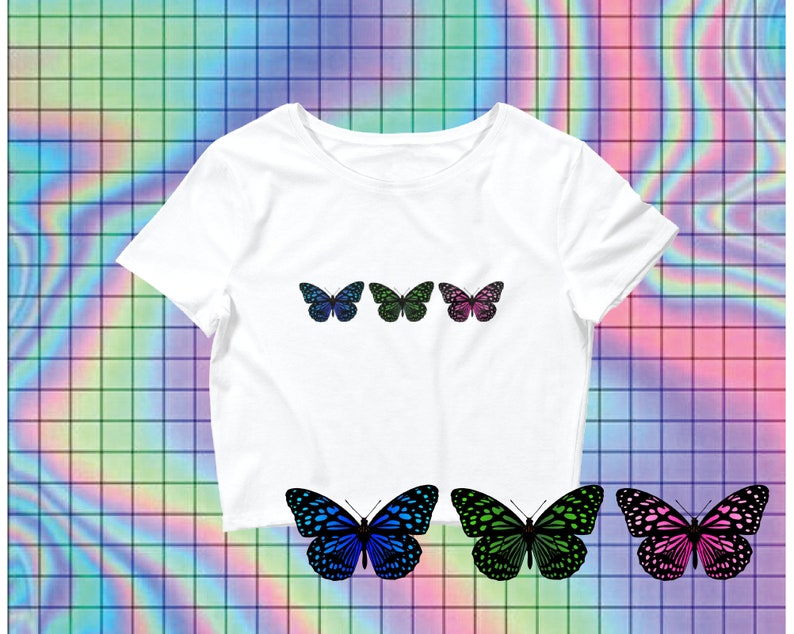 May include: White crop top with three butterfly designs. The butterflies are blue, green, and pink with black outlines.
