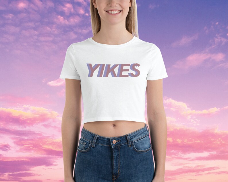 May include: White cropped t-shirt with the word "YIKES" printed in a purple and pink gradient.