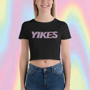 May include: A black cropped t-shirt with the word "YIKES" printed in pink and blue letters.