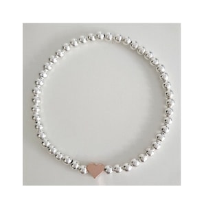 May include: A silver beaded bracelet with a small rose gold heart charm.