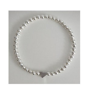 May include: A silver beaded bracelet with a small heart charm.
