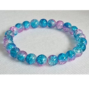 May include: A blue and pink glittery glass bead bracelet. The beads are round and have a speckled appearance.