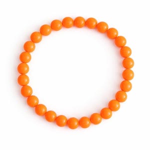 May include: A bright orange beaded bracelet. The bracelet features numerous round, evenly spaced beads. The beads are a solid, bright orange colour, creating a cheerful accessory. The bracelet is designed to be worn around the wrist. The beads are approximately 0.8 cm in diameter.