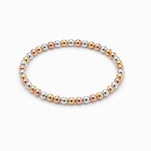 May include: A circular stretch bracelet composed of alternating polished spherical beads in yellow gold, rose gold, and silver tones. The beads are arranged in a repeating pattern, creating a continuous loop of metallic spheres with a reflective finish.