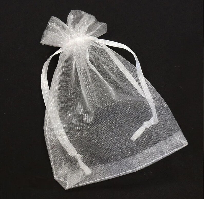 May include: A sheer white organza gift bag with a drawstring closure. The bag is made of a delicate, semi-transparent fabric and is tied at the top with a matching white ribbon. The bag is empty and ready to be filled with small gifts or favors.