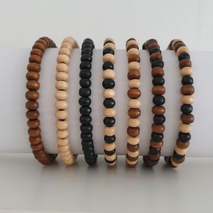 May include: Six wooden bead bracelets in various colours, including black, brown, and beige. The bracelets are stacked on top of each other.
