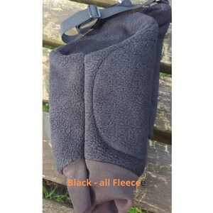 May include: Black fleece knee pad with a strap. The knee pad has a padded area on the back.