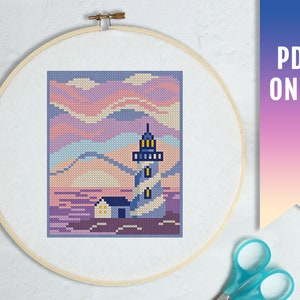 Könnte beinhalten: Ein Kreuzstichmuster mit einem Leuchtturm mit einem blau-weiß gestreiften Turm, einem kleinen Haus und einem rosa-violetten Sonnenuntergang.