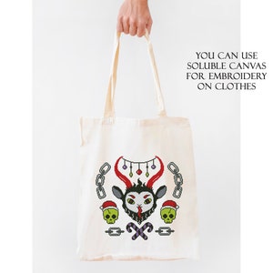May include: A white tote bag with a black and red embroidered design of a goat head with horns, candy canes, and skulls. The text "YOU CAN USE SOLUBLE CANVAS FOR EMBROIDERY ON CLOTHES" is printed on the bag.