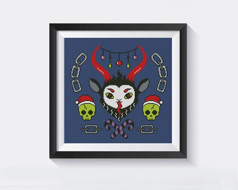 May include: A framed cross-stitch design featuring a cartoon goat with red horns, a black beard, and a tongue sticking out. The goat is wearing a Santa hat and surrounded by Christmas ornaments, candy canes, and chains.