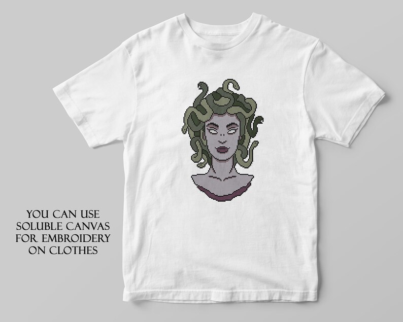 May include: White t-shirt with a pixelated image of Medusa, a mythical Greek figure with snakes for hair. The text "YOU CAN USE SOLUBLE CANVAS FOR EMBROIDERY ON CLOTHES" is printed below the image.