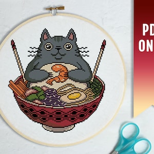 Peut inclure: Un chat noir avec un ventre blanc est assis dans un bol rouge de nouilles ramen. Le chat tient une crevette dans ses pattes. Le bol est décoré d'un motif noir et blanc.