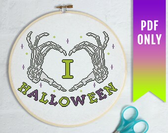Könnte beinhalten: Kreuzstichmuster mit zwei Skeletthänden, die ein Herz bilden, mit dem Text "Ich liebe Halloween" in grüner und violetter Schrift.