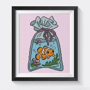 May include: A cross-stitch pattern of a blue and white bag with a purple ribbon, containing a small orange and white fish with bubbles. The bag is on a pink background.