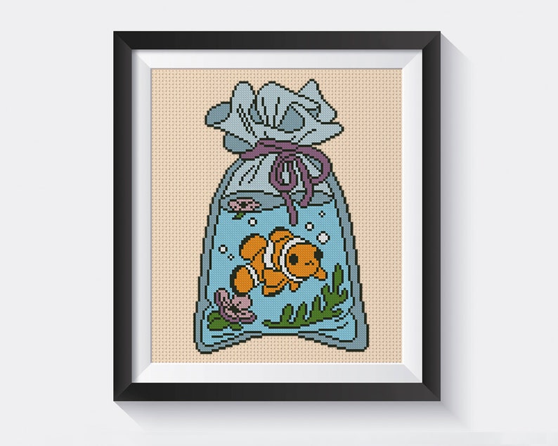 May include: A cross-stitch pattern of an orange and white clownfish swimming in a blue plastic bag with a purple ribbon tied around the top.