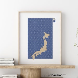 Puede incluir: Una impresión de un mapa de Japón con un fondo de patrón geométrico azul y blanco. El mapa es de color marrón claro y el texto "日本" está en la esquina superior derecha de la impresión. La impresión está enmarcada en un marco de madera claro y está colgada en una pared blanca.