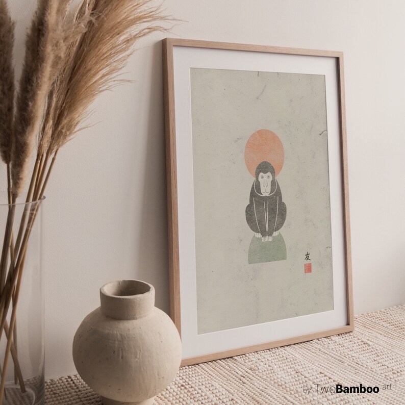 May include: A framed print with a minimalist illustration of a monkey sitting on a green circle with a red circle behind it. The background is a light beige with a textured look. The Japanese character "友" is printed in red in the bottom right corner.