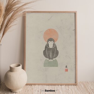 May include: A framed print of a black and white monkey sitting on a green circle with a peach colored circle above it. The print has a light green background and the Japanese character for "friend" in red.