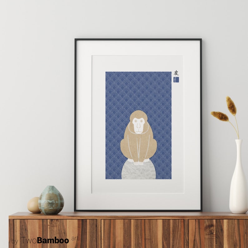 May include: A framed print of a brown monkey sitting on a rock against a blue background with a repeating pattern of white waves. The Japanese character for "friend" is in the top right corner of the print.