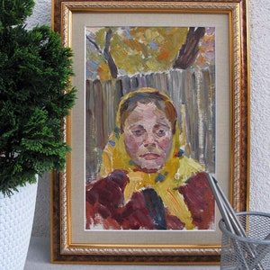 May include: A framed oil painting of a woman wearing a yellow headscarf. The woman has a serious expression on her face and is looking directly at the viewer. The painting is set against a background of a wooden fence and trees.