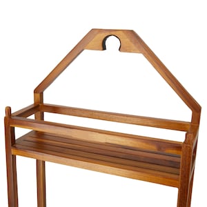 Puede incluir: Estanter&iacute;a de madera con parte superior en forma de casa y dos estantes. La unidad est&aacute; hecha de madera de color marr&oacute;n claro y tiene un acabado natural. La parte superior presenta un recorte para colgar. Los estantes tienen un dise&ntilde;o de listones.