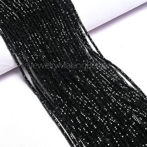 以下が含まれることがあります： 小さな黒いファセットビーズの複数のストランドのクローズアップ。ビーズは一緒にひもでつながれ、濃く暗い塊を形成しています。画像には「JewelryMakingBeads」というテキストが含まれています。
