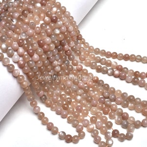 以下が含まれることがあります： 薄い茶色のサンストーンビーズのストランド。ビーズは丸く、滑らかで磨かれた仕上げになっています。ビーズは透明な糸に糸で通されています。