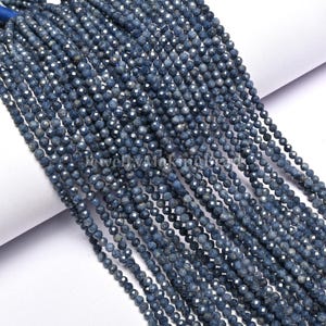 Può includere: Fili di perline di zaffiro blu scuro sfaccettate. Le perline sono piccole e rotonde, con molteplici sfaccettature che catturano la luce. L'immagine include il testo "JewelryMakingBeads".
