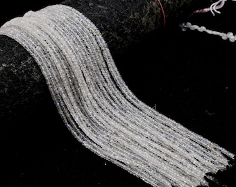 May include: A strand of white moonstone beads, approximately 2mm in size, with a slight iridescent shimmer. The beads are strung on a clear thread and are arranged in a loose, flowing pattern.