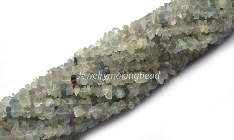May include: A strand of light green, blue, and purple fluorite chip beads. The beads are irregular in shape and have a natural, tumbled finish.