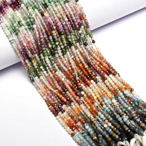 Könnte beinhalten: Stränge aus kleinen, facettierten Perlen in verschiedenen Farben, darunter Grün, Rosa, Orange und Lila. Die Perlen sind aufgefädelt und bilden eine strukturierte und farbenfrohe Darstellung. Ideal für die Schmuckherstellung oder Bastelprojekte.