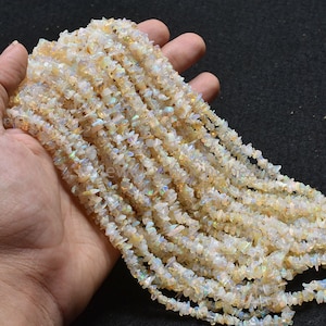 May include: A strand of white opal chip beads with iridescent shimmer. The beads are irregular in shape and size, and are strung on a clear thread.