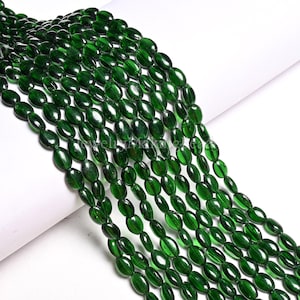May include: Strands of dark green oval-shaped beads. The beads are strung together, creating a flowing, organic pattern. The beads have a glossy finish, reflecting light and adding depth to the color. Ideal for jewelry making.
