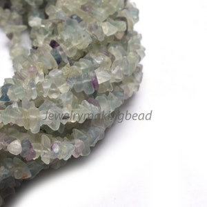 May include: A strand of light green, blue, and purple fluorite chip beads. The beads are irregular in shape and have a natural, polished finish.