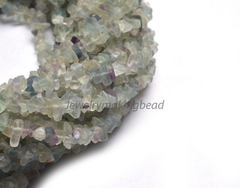 May include: A strand of light green, blue, and purple fluorite chip beads. The beads are irregular in shape and have a natural, polished finish.