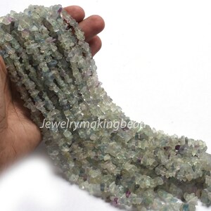 May include: A strand of light green, blue, and purple fluorite chip beads. The beads are irregular in shape and size, and they are strung on a clear thread.