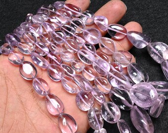 May include: A strand of light purple amethyst gemstone beads, each bead is oval shaped and smooth. The beads are strung on a clear thread.