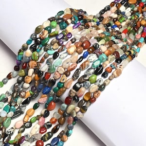 May include: Strands of colorful gemstone beads in various shapes and sizes. The beads display a mix of colors including green, blue, red, brown, and white. The beads are strung together, ready for jewelry making or crafting.