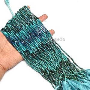 Puede incluir: Un largo hilo de pequeñas cuentas redondas y facetadas en tonos variados de turquesa, verde azulado y azul profundo. Las cuentas están ensartadas en múltiples filas paralelas, con una borla de color azul claro en el extremo del hilo.