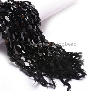 May include: A strand of black faceted gemstone beads with a black tassel. The beads are approximately 8mm in size and have a slightly irregular shape.