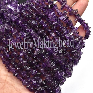 May include: A strand of purple amethyst chip beads. The beads are irregular in shape and have a natural, rough texture. The beads are strung on a clear thread and are ready to be used for jewelry making.