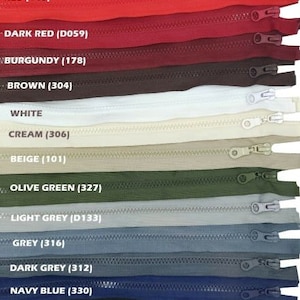 May include: A range of coloured zippers, including red, dark red, burgundy, brown, white, cream, beige, olive green, light grey, grey, dark grey, navy blue, and black. Each zipper has a metal pull, with colour names and codes above.