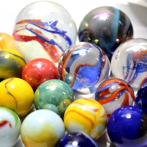 Peut inclure: Une collection de billes de verre colorées de différentes tailles. Les billes présentent des tourbillons rouges, bleus, jaunes et verts. Certaines billes sont transparentes, d'autres opaques avec des motifs vibrants.