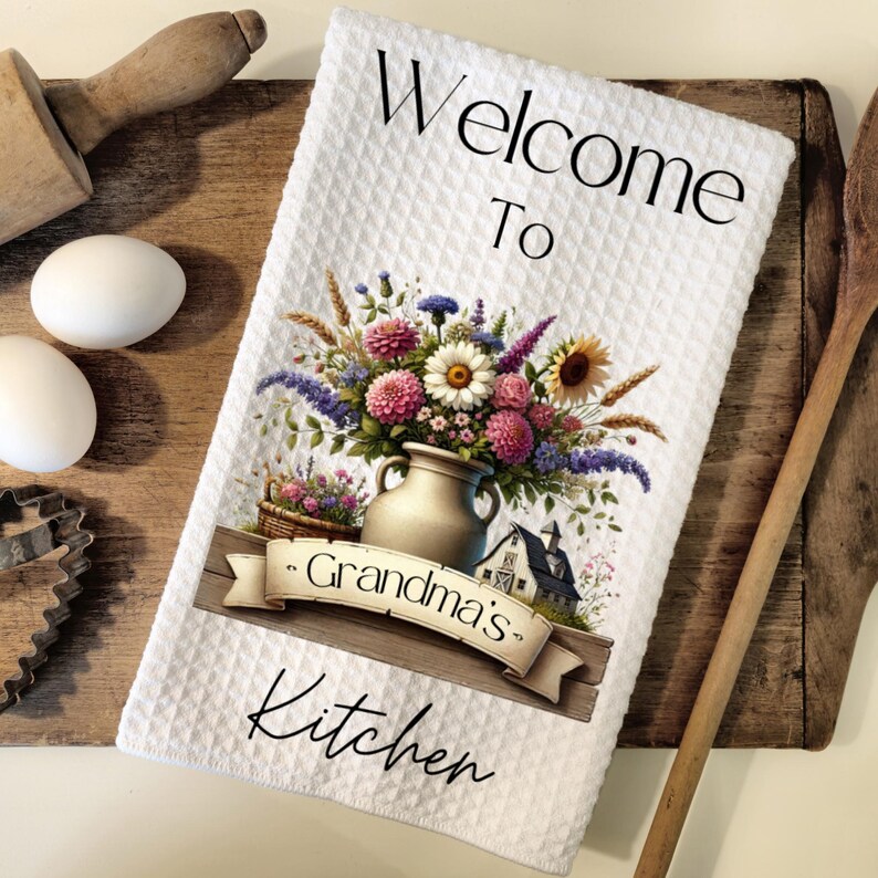 Puede incluir: Toalla de cocina blanca con un dise&ntilde;o floral y el texto "Bienvenido a la cocina de la abuela".